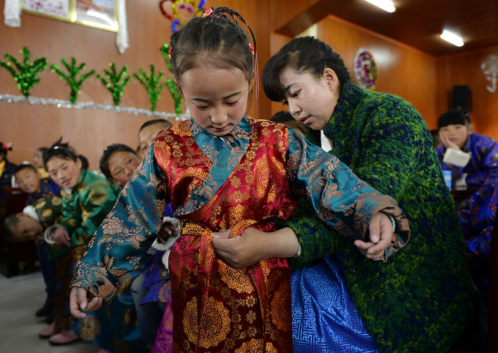 2月27日，在西藏自治區(qū)兒童福利院，來自拉薩市尼木縣的“愛心媽媽”德慶旺姆（右）在為來自那曲地區(qū)的嘎瑪曲宗換上節(jié)日盛裝。