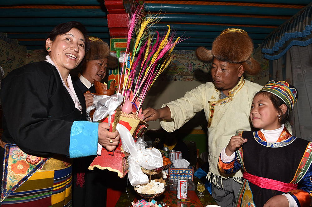 2月27日，拉薩市城關(guān)區(qū)阿壩林卡社區(qū)居民央拉（左）向鄰居敬獻(xiàn)“切瑪”。